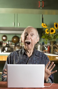 Shocked Senior Man in Dining Room with a Laptop Computer